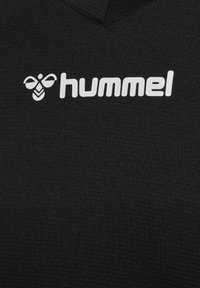 Schwarzes Sportshirt mit V-Ausschnitt, aus strukturiertem Stoff, mit einem weißen "hummel"-Logo und einem Bienensymbol auf der Vorderseite.
