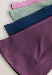 Hromada štyroch zložených bavlnených tričiek v farbách mauve, námornícka modrá, šalviovo zelená a svetloružová na svetlom povrchu.