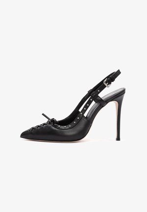 Chaussure à talon haut en cuir noir avec un bout pointu, des détails en dentelle décoratifs et des clous en métal le long de la sangle de la cheville.