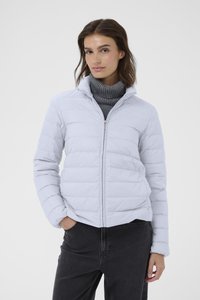 Helle graue Pufferjacke mit hohem Kragen, horizontalen Steppdesign, durchgehendem Reißverschluss und langen Ärmeln. Über einem grauen Rollkragenpullover getragen.