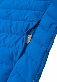 Giacca isolante blu con design a cuciture trapuntate, dotata di tasca con zip e texture liscia. Le cuciture a vista aggiungono dettagli.