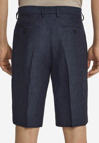 Mörkblå linnebyxor med en texturerad yta, med två bakfickor med knappstängning och en rak skärning.