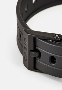 Bracelet de montre en caoutchouc noir avec une surface texturée, boucle ajustable avec 'CASIO' en relief et plusieurs trous pour la personnalisation de la taille.