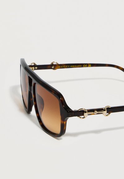 Ορθογώνια γυαλιά ηλίου με σχέδιο χελώνας, φακούς με καφέ διαβάθμιση και χρυσή διακόσμηση με μοτίβο αλόγου στις βραχίονες.