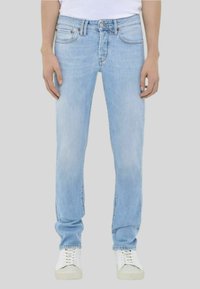 Jeans in denim blu chiaro con taglio dritto, dotati di cinque tasche, chiusura con bottone e leggero sbiadimento. Indossati con sneakers bianche.