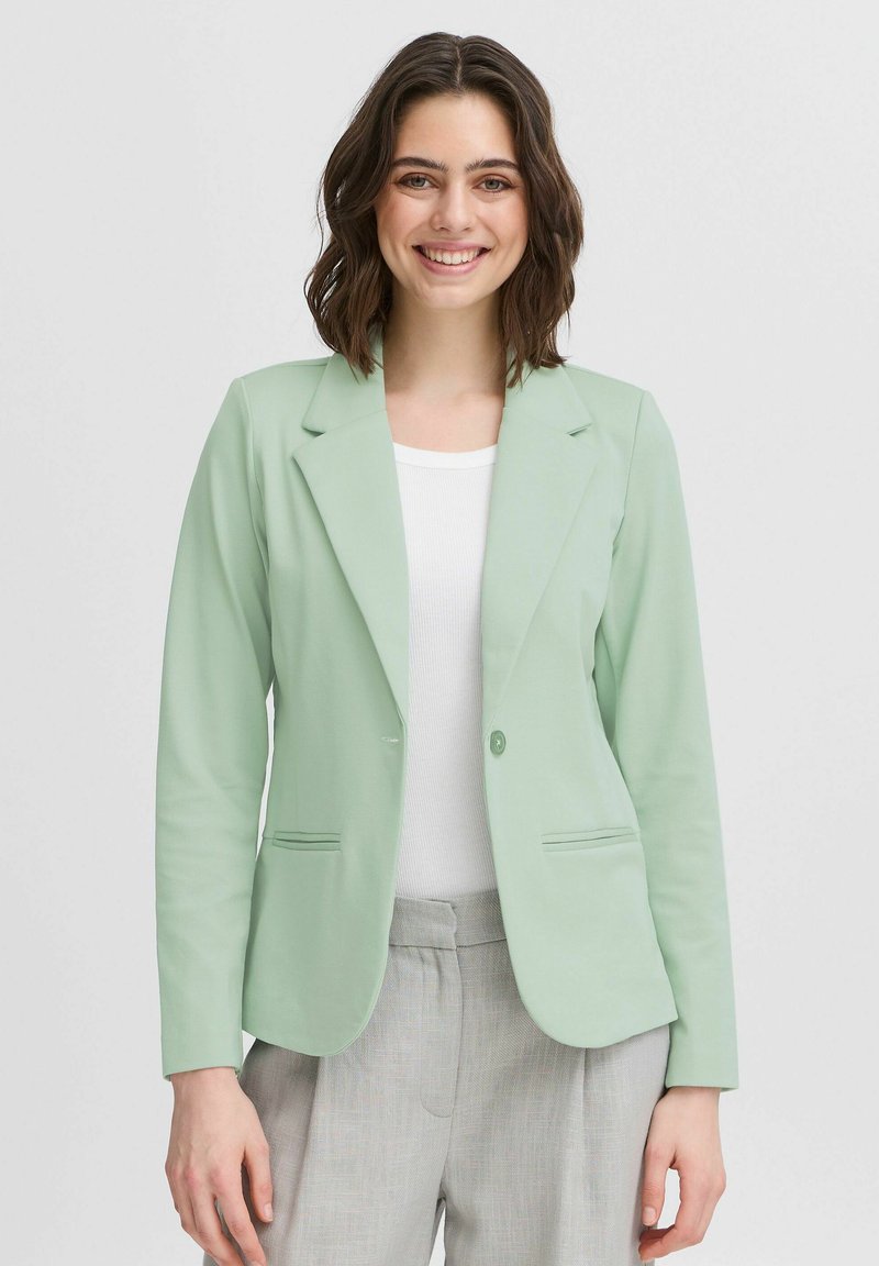 Mátově zelený blazer vyrobený z hladké tkaniny, s klasickým designem klopy, dvěma předními kapsami a jedním knoflíkovým zapínáním.