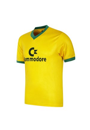 Yellow short-sleeve shirt with green collar and sleeve edges, featuring a black "Commodore" logo and lettering on the front.