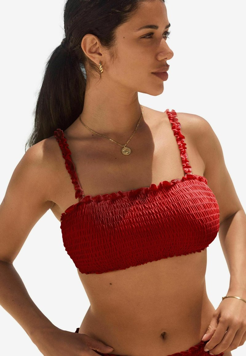 Piros fodros bikini felső ráncolt szélekkel és vékony, állítható pántokkal. A texturált anyag testhez simuló, összegyűrt megjelenést biztosít.