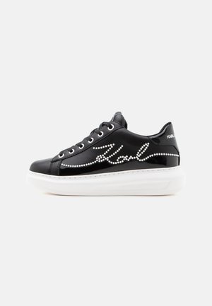 Czarny skórzany sneaker z białą platformą, białe ćwieki tworzące napis "Karl" z boku oraz czarne sznurowadła z metalowymi oczkami.