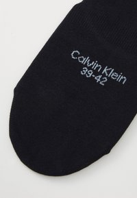 Μαύρη βαμβακερή κάλτσα με ριγέ κορυφή, χωρίς ραφή στη μύτη και ανοιχτό μπλε κείμενο που αναγράφει "Calvin Klein" και μέγεθος 39-42.