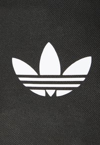 Fondo de tela negra con un distintivo logo trefoil blanco que presenta tres hojas y tres franjas horizontales.