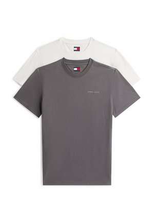 Dwie składane koszulki Tommy Jeans, jedna szara z logo na piersi, a druga biała, ułożone warstwowo z szarą koszulką z przodu na białym tle.