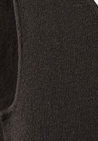 Gros plan d'un tissu tricoté marron foncé montrant la texture détaillée et le motif de point d'un vêtement doux et chaud.