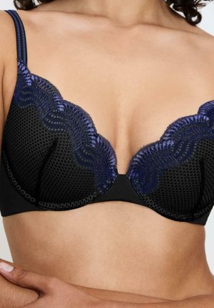 Sostén negro con tela de malla texturizada, borde de encaje morado, bordes con forma de ola y tirantes ajustables. El diseño con aros realza el soporte.