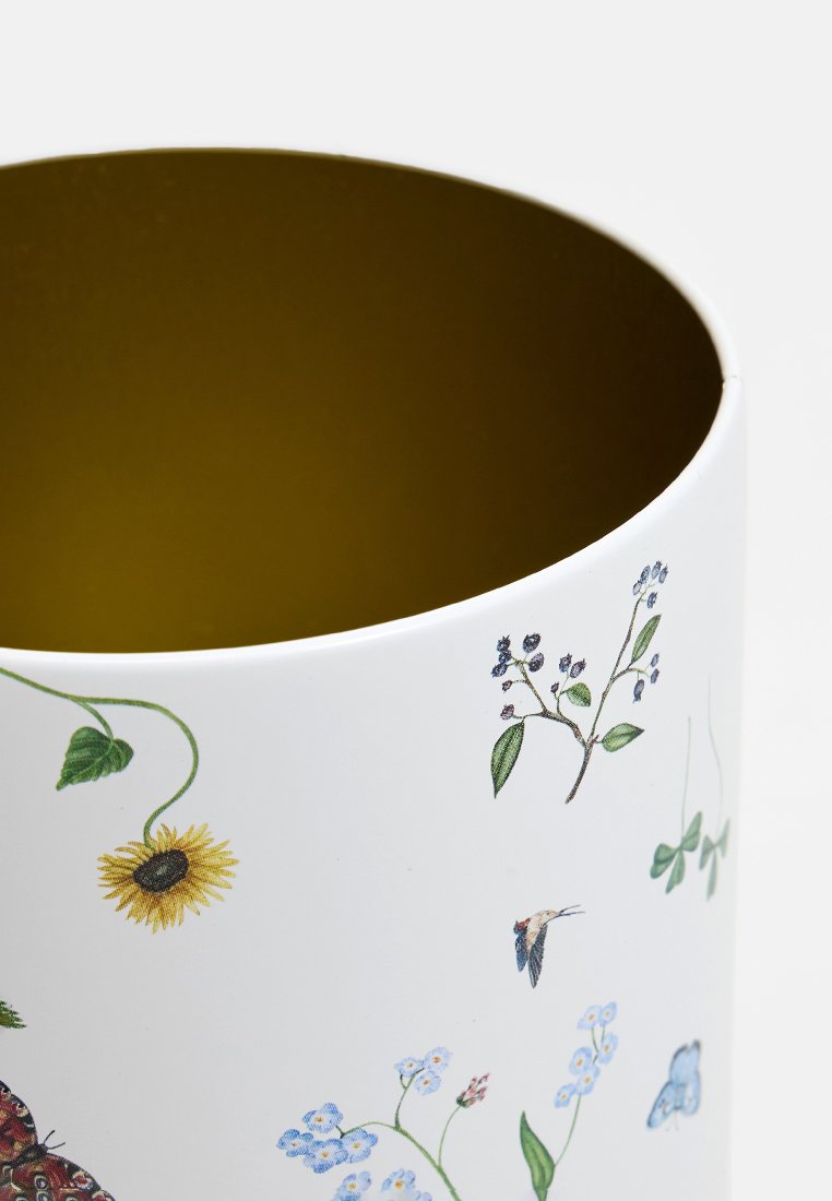 Witte cilindrische container met botanische illustraties, waaronder bloemen en vlinders, met een glanzende gouden binnenkant.
