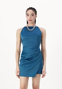 Vestido de cetim verde-água com decote halter e detalhes franzidos. Apresenta um efeito drapeado na frente, corte até ao joelho e textura suave.