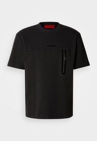 Svart T-skjorte med korte ermer og rund hals, med en frontlomme med glidelås, subtil logo på brystet, og en glatt tekstur.