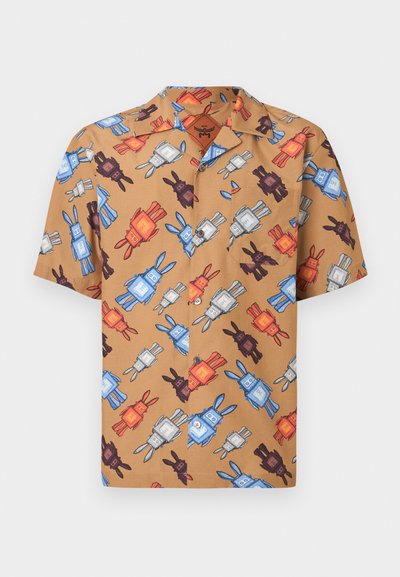 Chemise à manches courtes avec boutons, en tissu beige présentant un motif ludique de lapins multicolores et de robots en bleu, rouge, noir et blanc.