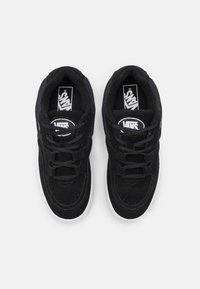 Černé semišové tenisky s síťovaným jazykem, plochými černými šňůrkami, bílými gumovými podrážkami a logy Vans na vnitřní straně a vnější straně.