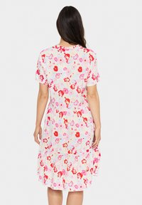Korte mouw floral jurk in crème met rode en roze bloemen. Vloeiende vorm, gathered taille en gelaagde rok. Lichtgewicht stof.