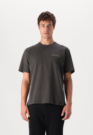 Camiseta de algodón gris oscuro con cuello redondo clásico, mangas cortas y un pequeño logo de "DICKIES" en el lado izquierdo del pecho. Diseño simple.
