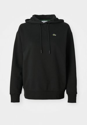 Zwarte hoodie van zacht materiaal, met een kangoeroezak, een capuchon met trekkoord en een klein groen Lacoste-logo op de borst.