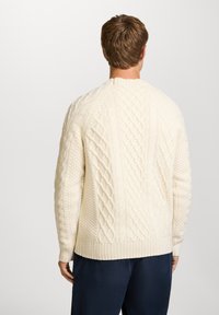Cremfarbener Kabelstrickpullover mit strukturierten Mustern, gerippten Bündchen und Saum, runder Halslinie und lässiger Passform.