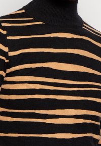 Pull à col roulé rayé noir et fauve. Présente une texture côtelée, avec des rayures de différentes épaisseurs et un design à col haut.