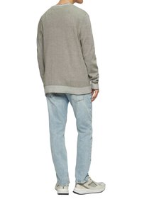 Jasnoszary sweter dzianinowy z długimi rękawami, okrągłym dekoltem i prążkowanym wykończeniem, zestawiony z jasnoniebieskimi dżinsami i szarymi butami sportowymi.