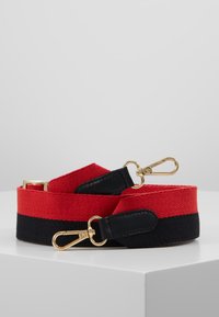 Cinghia in cotone rossa e nera con clip in metallo dorato. Presenta una texture intrecciata. Le estremità hanno dettagli in pelle nera. Dettaglio hardware rettangolare.