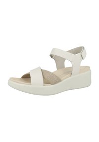 Sandale compensée blanche avec des sangles élastiques et en cuir. Elle présente un upper texturé et une semelle intérieure rembourrée. Semelle extérieure en caoutchouc légèrement surélevée.