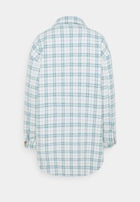 Koszula w kratę o białym tle z jasnobłękitnym wzorem siatki. Długie rękawy i klasyczny kołnierzyk. Miękka, teksturowana tkanina.