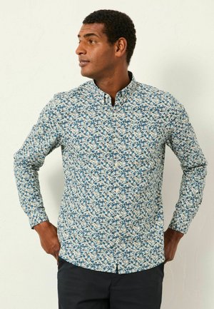 Langärmliges Hemd mit Knöpfen aus leichtem Stoff, das ein blaues Blumenmuster auf weißem Hintergrund zeigt, mit einem Spitzkragen und einem geraden Saum.