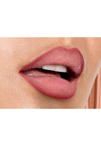 Matte roze lipkleur op ietsjes textuurde lippen, met een gladde afwerking en subtiele definitie, die de natuurlijke lipcontouren benadrukt.