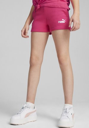 Pantaloni corti rosa in cotone con una texture liscia e vita elasticizzata, con logo Puma bianco. Abbinati a sneakers bianche e calzini alla caviglia.