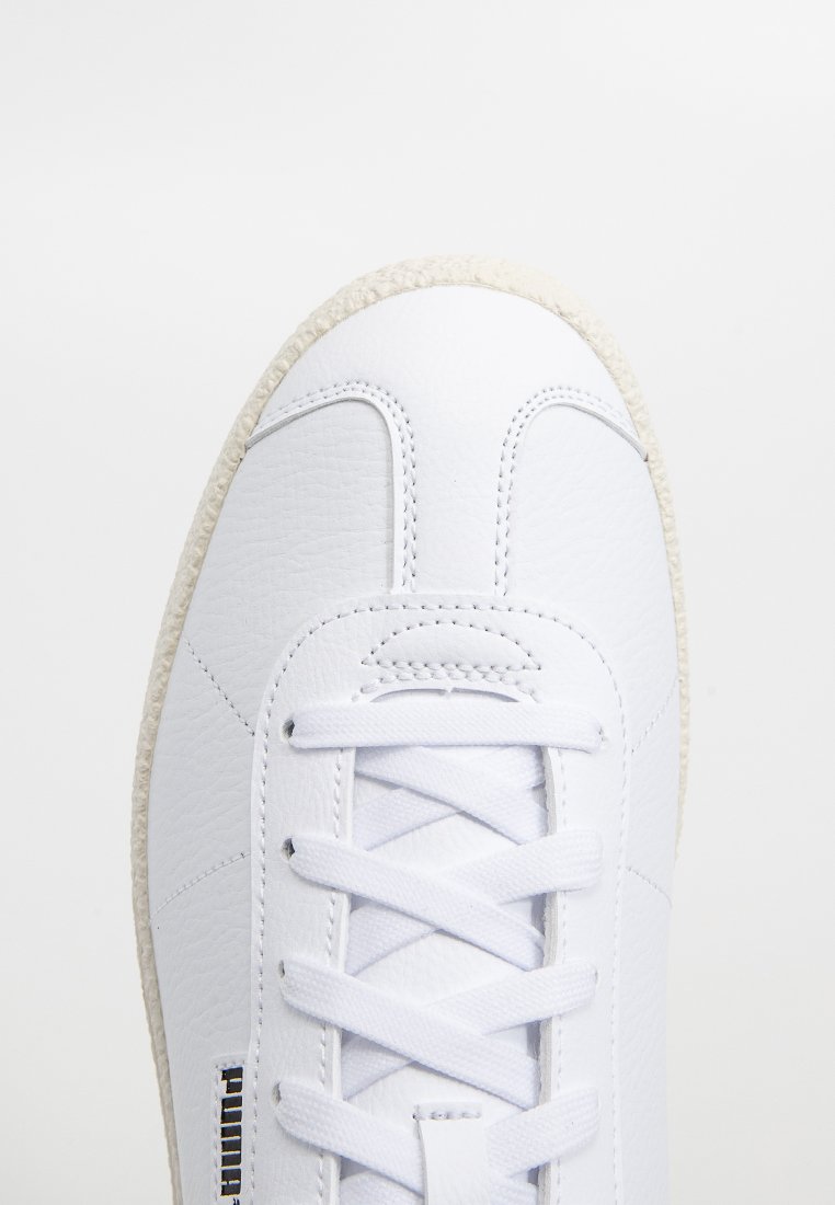 Białe skórzane sneakersy z okrągłym noskiem, teksturowaną powierzchnią, płaskimi sznurówkami i beżową gumową podeszwą. Posiadają minimalistyczne detale w szwie.