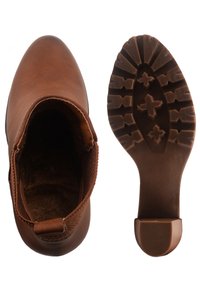 Botín de tobillo de imitación cuero marrón con paneles laterales elásticos y suela de goma texturizada. Interior forrado con material suave para mayor comodidad.