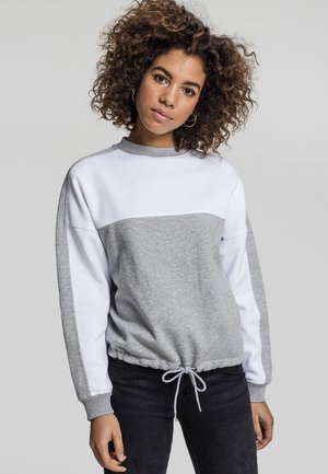 Grå og hvit fargeblokkert sweatshirt med rund hals, elastisk kant og snøre detaljer. Stoffet ser mykt og teksturert ut.