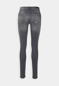 Jeans ajustados de denim gris oscuro, con cintura alta, dobladillo desflecado y dos bolsillos traseros. Textura suave con sutiles detalles de desgaste.