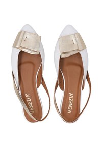 Białe, szpiczaste buty na obcasie z złotym metalicznym kokardką, otwarte po bokach i z beżową wkładką, z paskiem typu slingback.