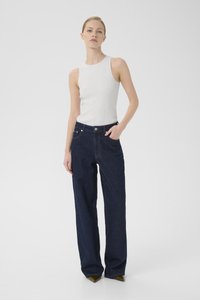 Hvit ermeløs topp med ribbet tekstur, parret med mørkeblå vidjeans med metallknapp og lommer. Nøytral bakgrunn.