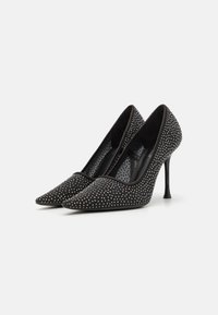 Sorte højhælede pumps med spidse tæer, prydet med sølvnitter, der har en glat tekstur og en slank, spidset silhuet.