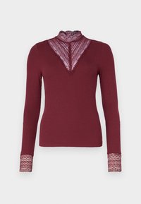 Burgundy långärmad topp med en spets V-ringning och hög krage. Ribbad textur, spetsdetaljer vid ärmar och halsringning. Åtsittande design.