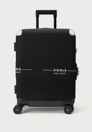 Valise rigide noire avec quatre roues pivotantes, poignée rétractable et une sangle en tissu de marque indiquant "FPM Milano."