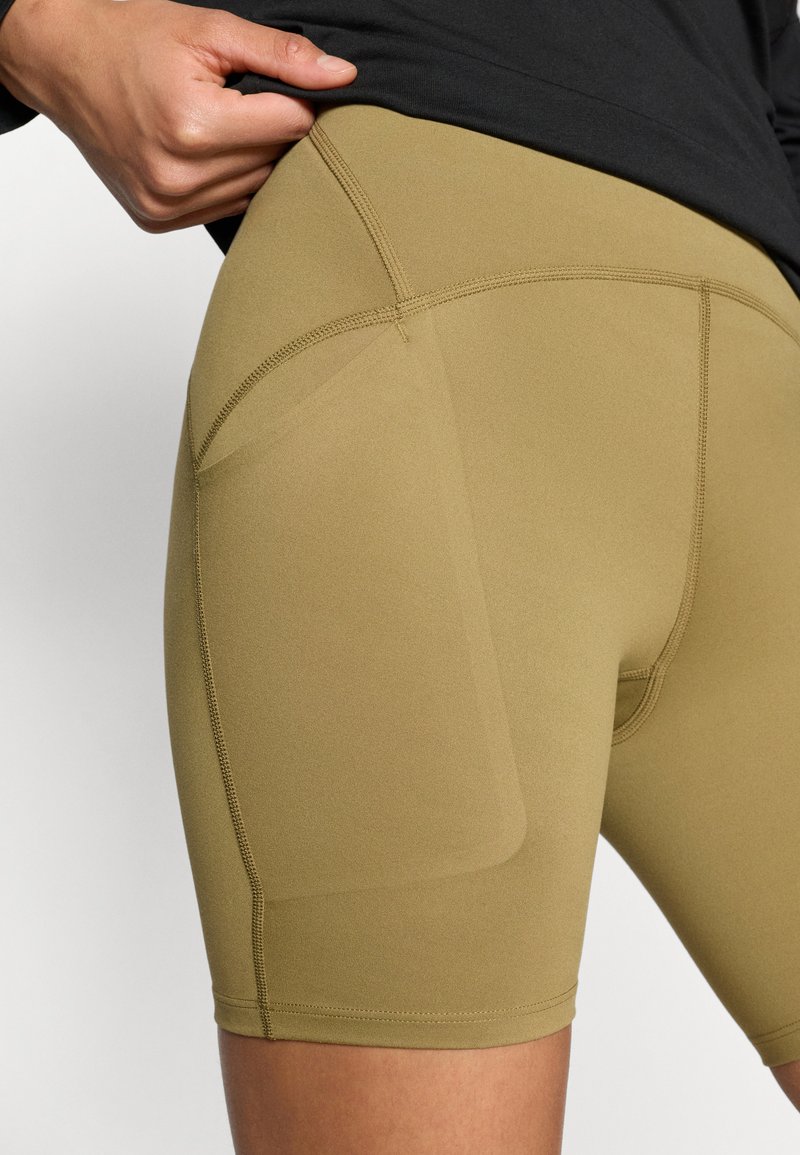 Olivgröna träningsshorts gjorda av stretchigt, mjukt tyg. Har en sidoficka och flatlock-sömmar för komfort.