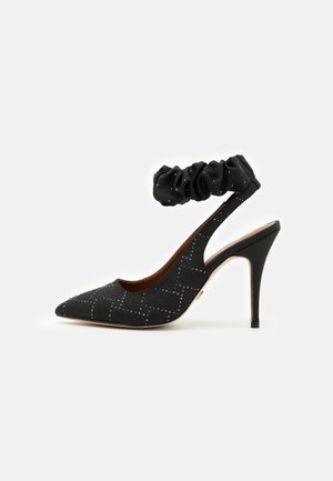 Chaussure noire à talon haut avec bout pointu, motif clouté et bride de cheville froncée.