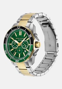 Žalias ciferblatas su auksine ir nerūdijančio plieno apyranke. Yra chronografo ciferblatai, juodas rėmelis ir atsparumas vandeniui iki 100 metrų.