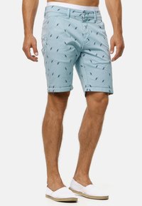 Light blue shorts featuring a printed pattern of small birds. Made of lightweight fabric with side pockets and cuffed hems.