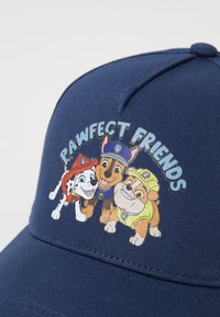 Jūros laivyno skrybėlė su audinio tekstūra, kuriame pavaizduoti trys šunys, iliustruojami spalvinguose animaciniuose grafikuose su tekstu "PAWfect Friends".