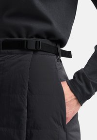 Zwarte, gevoerde thermobroek met een ronde taille, voorzien van een zwarte verstelbare riem en een zijzak. Zachte, gestructureerde stof.